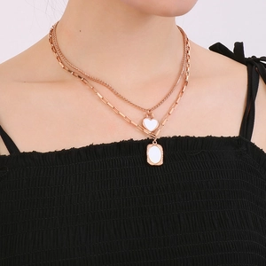 Detail of rose gold double-layered necklace with white heart and oval pendants on model
