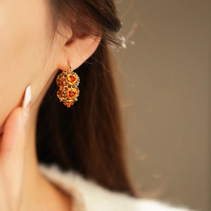 Detailed view of vintage gold-plated hoop earring with orange rose and crystal inlay