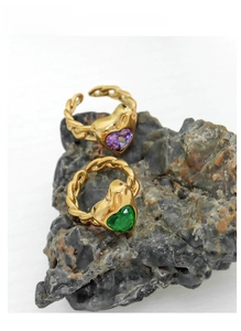 Detail of gold titanium steel open rings with purple and green heart-shaped gemstones