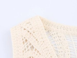 Vista macro dettagliata del gilet in maglia all'uncinetto crema con trama geometrica fine