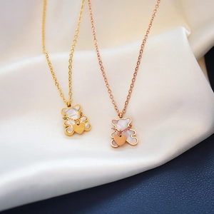 Titanium steel bear pendant necklaces in gold and rose gold on white silk fabric