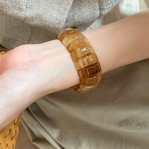 Macro shot of an amber resin elastic bracelet showing the smooth texture and gloss finish