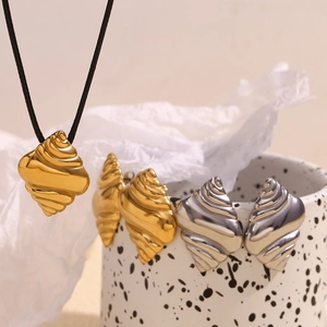 Detail of 18K gold and silver seashell pendants with wax rope necklace on ceramic