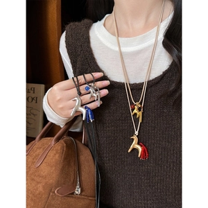 Detail of horseshoe pony pendant necklace with colorful tassels and metallic finish