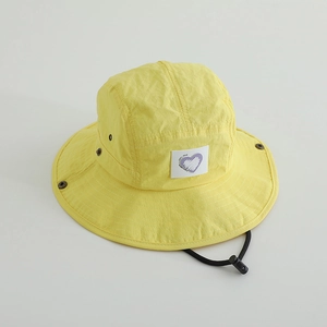 Detail of yellow kids bucket hat featuring a purple heart patch and adjustable wind cord