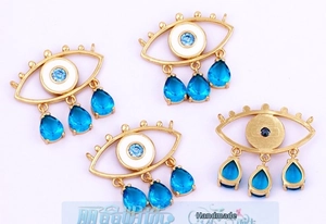 Macro view of gold-plated evil eye charms with blue zircon stones and matte back finish