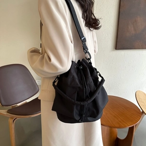 Détail d'un sac seau noir en nylon avec cordon de serrage porté par un mannequin