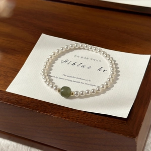 Detailed macro view of Hetian jade bead and white pearls on a display card holder