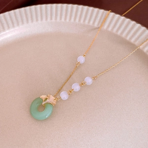 Détail du pendentif feuille de ginkgo avec anneau de jade et perles sur chaîne dorée