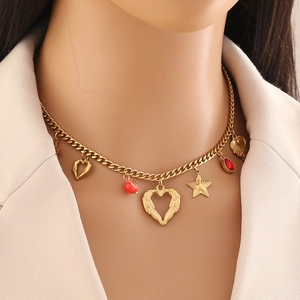 Dettaglio di una collana dorata con ciondoli a cuore e stella e perline rosse su catena
