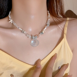 Detail of beaded necklace with starfish accents and a translucent shell pendant worn on neck