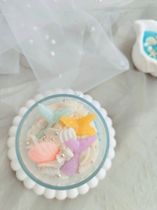 Detailed top view of mermaid tail and shell decorations on cream candle top
