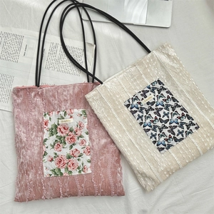 Detailed top view of velvet tote bags featuring delicate floral and butterfly patches