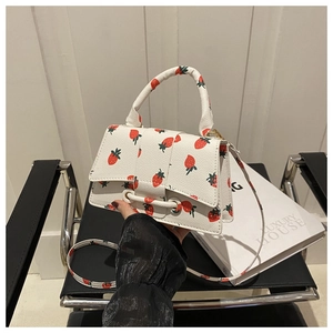 Detail van een witte leren handtas met aardbeienprint en gespsluiting voor dames
