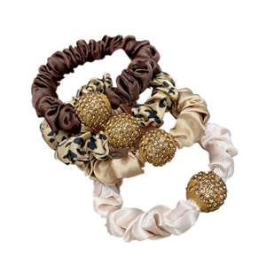 Set of four satin scrunchies in leopard print and solid colors with rhinestone gold beads