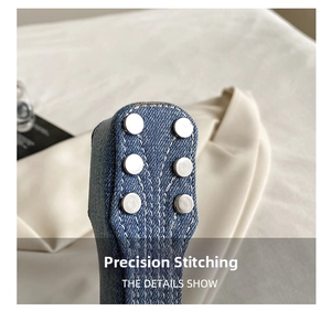 Macro detail of dark blue washed denim with silver rivets and precision white stitching