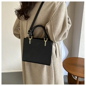 Close-up of a black leather handbag with golden metal hardware and stitch detail