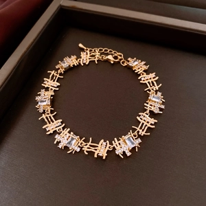 Close-up of golden Xi-character link bracelet with sparkling zircons in a jewelry box