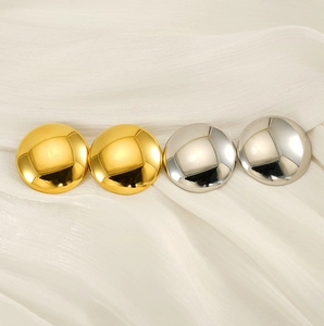 Gros plan de boucles d'oreilles rondes dorées et argentées sur soie blanche
