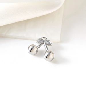 Polished silver stainless steel cherry pendant jewelry piece on white fabric