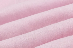 Close-up of pink linen fabric texture showing high-quality plain weave and fiber details