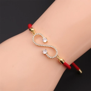Macro detail of red woven rope bracelet with gold infinity charm and white cubic zirconia