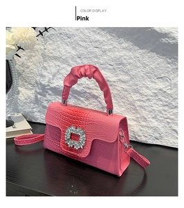 Close-up of pink croc-effect handbag featuring a crystal buckle and ruffled handle