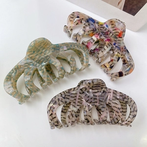 Macro detail of three acetate hair claws in green, purple, and colorful textured patterns