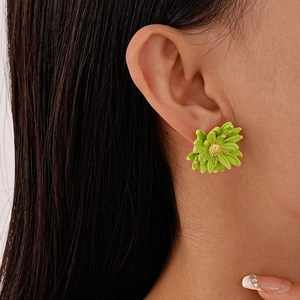 Close-up of green daisy flower earring with golden center on model's ear
