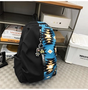 Detail of black canvas backpack with colorful geometric pattern and astronaut pendant