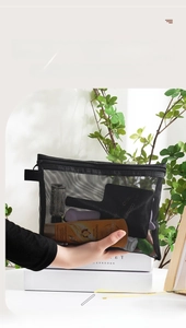 Detail of hand holding a black mesh nylon cosmetic pouch with breathable zipper closure