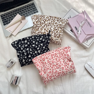 Detail of three-piece corduroy leopard heart makeup bags on a minimalist desk setup
