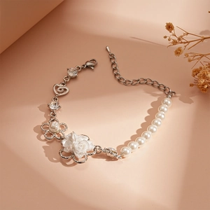 Dettaglio di un bracciale con perle bianche e un elemento floreale tridimensionale