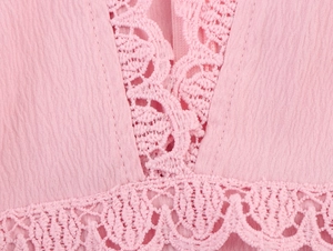 Detail of pink dress featuring delicate lace stitching and textured pleated fabric surface