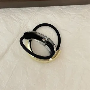 Detail of minimalist hair tie featuring dual-tone gold and silver metallic crescent accents