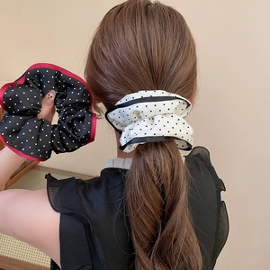 Close-up of polka dot fabric scrunchies showing elegant pleats and smooth silk texture