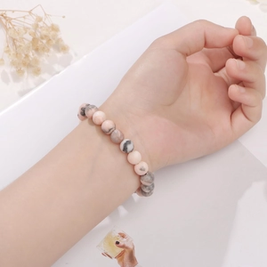 Gros plan d'un bracelet en perles de pierre naturelle rose et grise porté au poignet