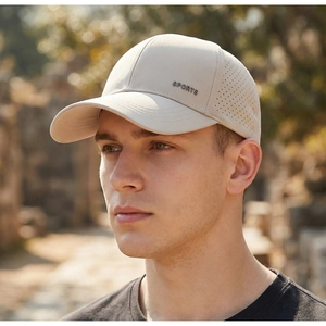 Detail of breathable laser-cut holes and metal SPORTS logo on a beige mesh baseball cap