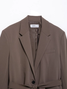 Close-up of the brand label on a dark brown women's casual suit jacket in size S