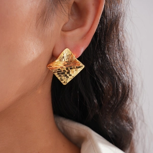 Detailed view of 18k gold plated rhombus earrings with unique hammered texture on model