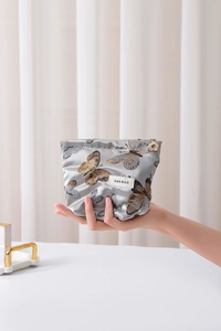 Detailed close-up of a silver butterfly makeup bag with a decorative flower zipper puller