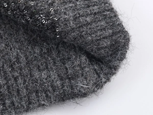Macro detail of dark grey knit fabric with sequin embellishments and mohair texture