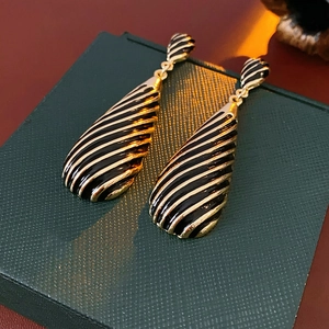 Gros plan de boucles d'oreilles vintage à rayures dorées et noires sur une boîte verte
