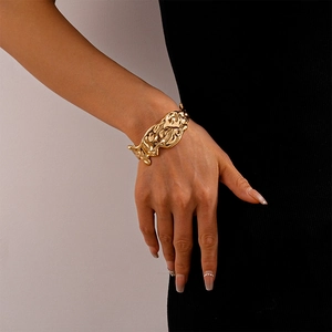 Detailed view of wide gold cuff bracelet featuring organic lava texture on a model wrist
