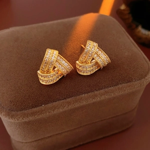 Détail de boucles d'oreilles triangulaires dorées avec zircons sur une boîte à bijoux en velours