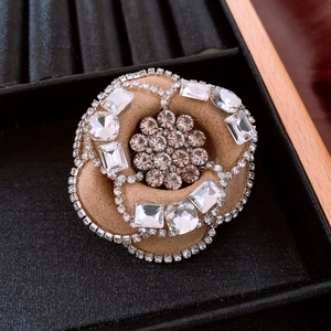 Close-up of vintage camel fabric camellia brooch with champagne rhinestones and velvet petals