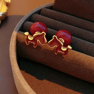 Macro shot of 18K gold plated red pony earring with pearl in a velvet jewelry box