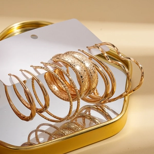 Ten-piece set of gold geometric hoop earrings with textured snake skin and wavy designs