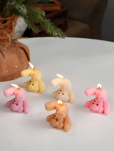 Detailed view of burning bear and poodle shaped scented candles in soft pastel colors