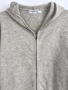 Detailed texture of light gray knitted fabric and zipper on a hooded cardigan